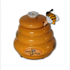 Beehive shaped honey pot, golden color, with a bee figurine at the end of the honey dipper.